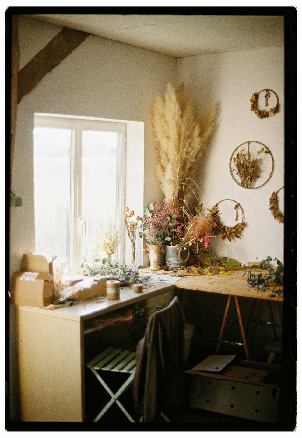 Crafting supplies and dried flowers on a rustic studio desk.